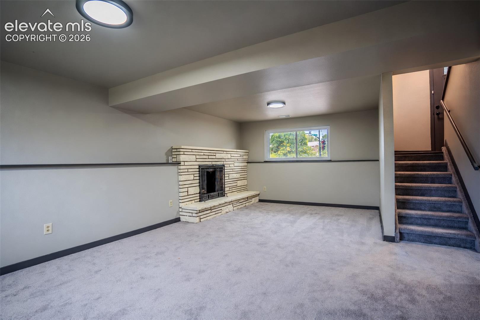 Stone-faced fireplace, wall-to-wall carpeting, and recessed ceiling lighting