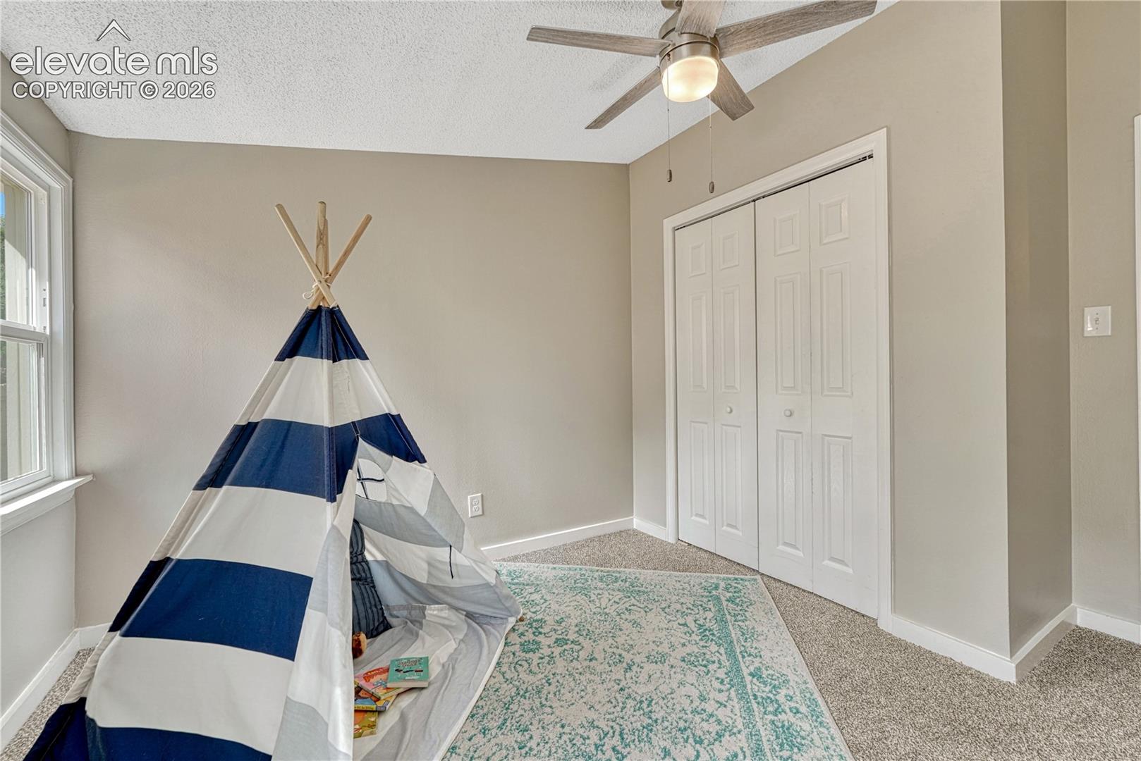 Bright bedroom with neutral wall finishes, carpet flooring, and abundant natural light from a large window