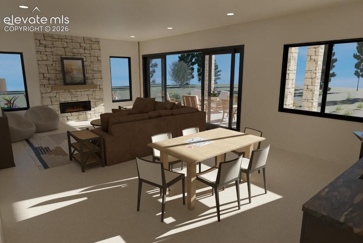 Open-concept family room featuring a stacked stone fireplace with an integrated electric insert, large sliding glass doors, multiple windows with black frames, recessed ceiling lighting, and light-toned flooring