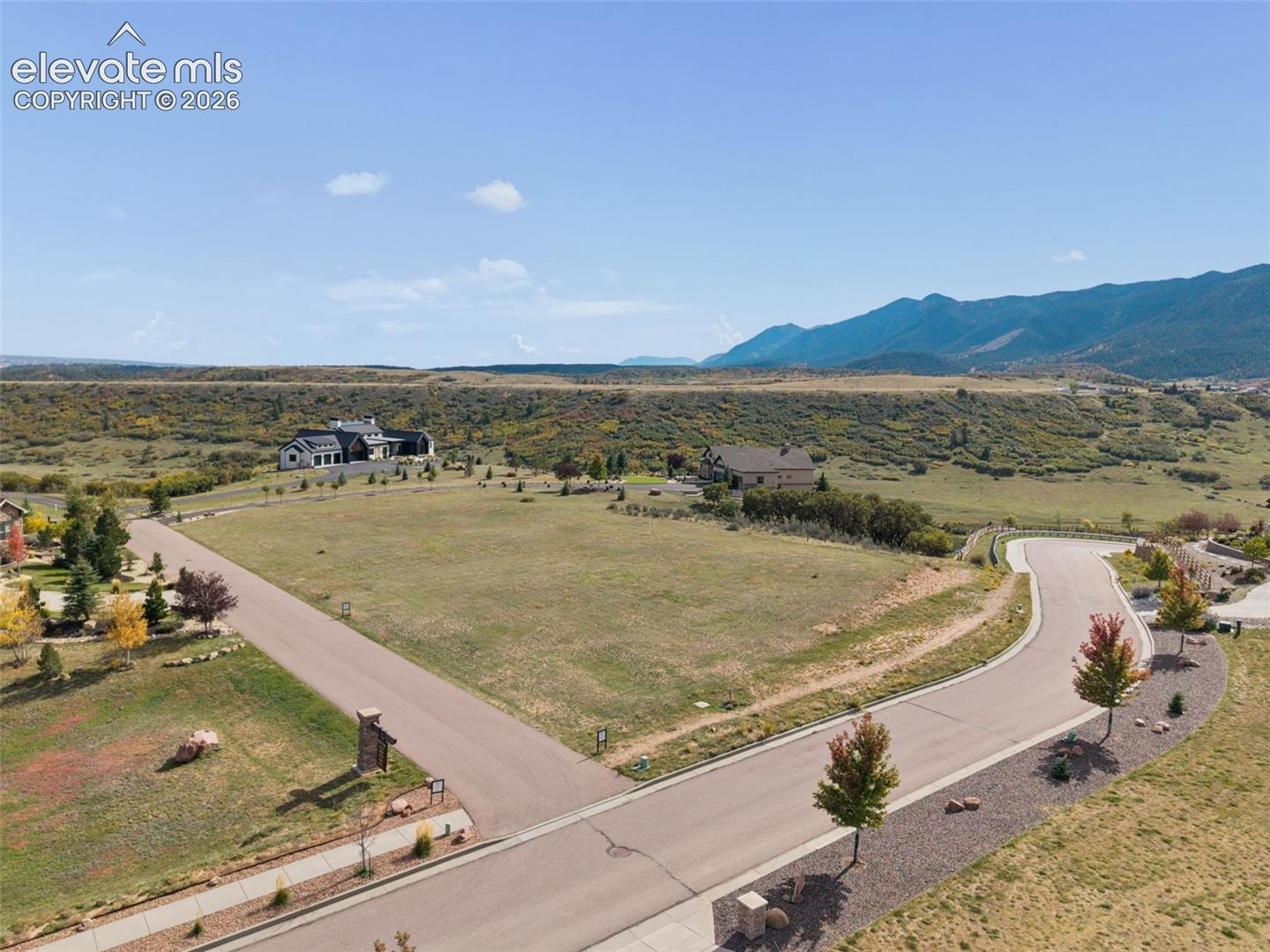 Expansive corner lot featuring paved road access, concrete sidewalks, and prominent mountain backdrops