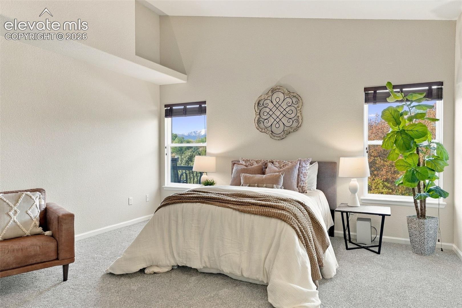 Vaulted ceiling, neutral wall tones, and dual windows with mountain scenery