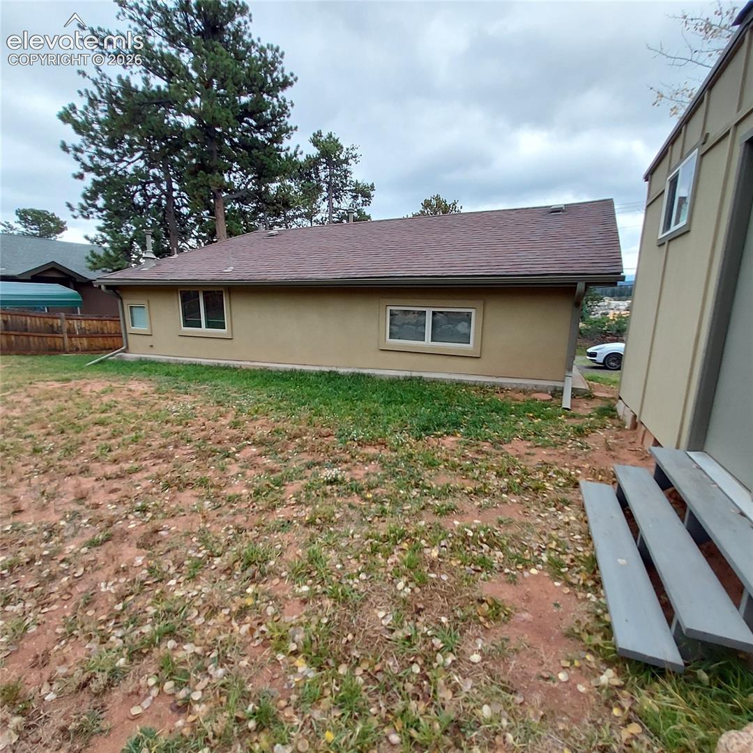 Exterior view featuring a stucco-finished structure with a pitched shingle roof, double-pane windows.