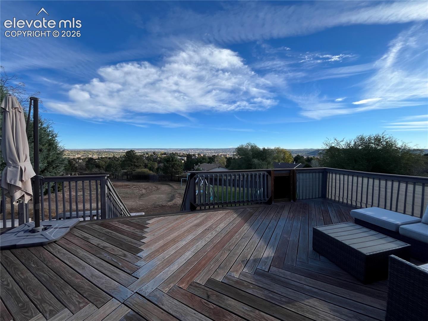 Elevated wood deck featuring a chevron plank pattern, vertical railing, and expansive horizon scenery