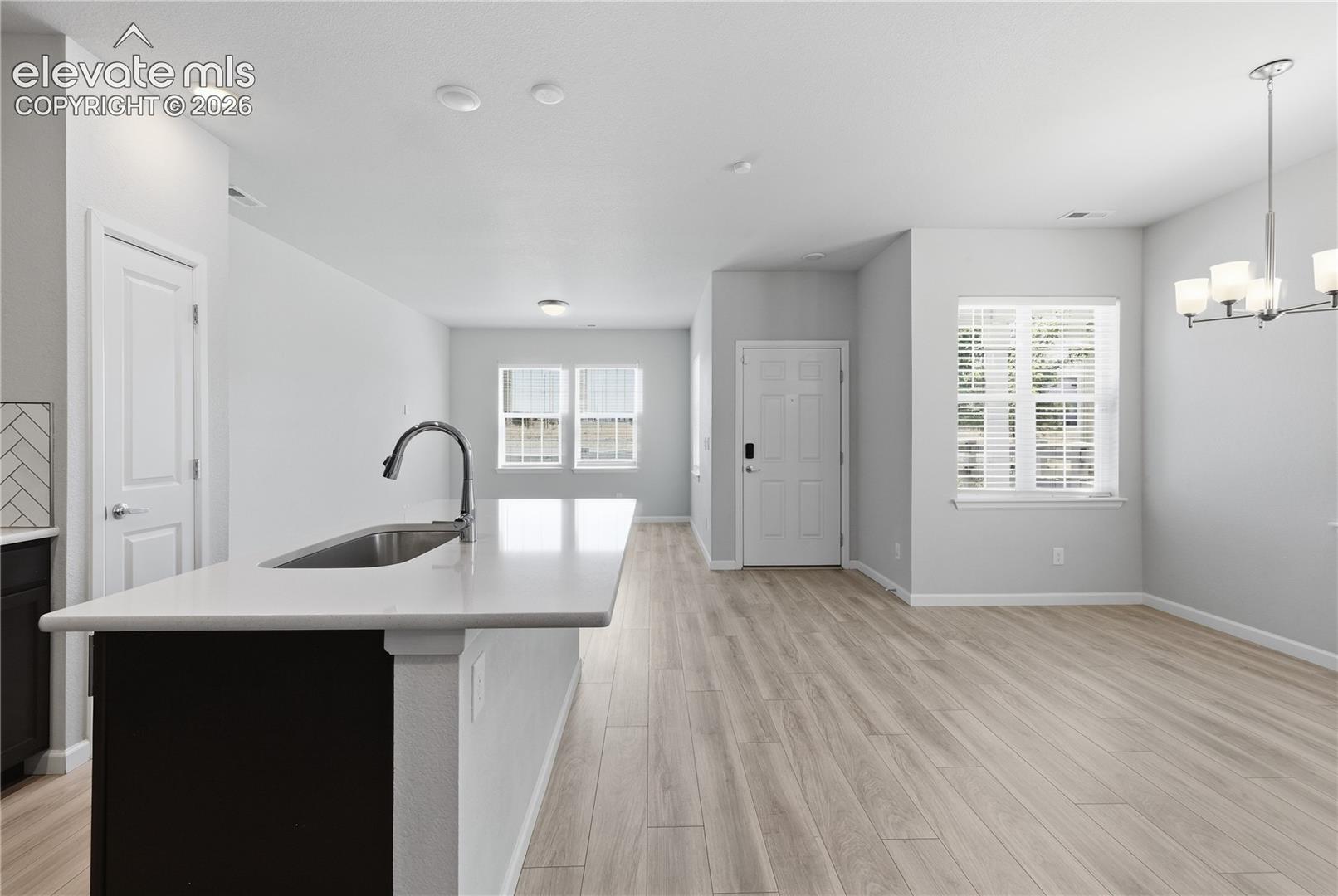 Open-concept living area featuring light wood-finish flooring, recessed lighting, and a kitchen island with an undermount sink and gooseneck faucet