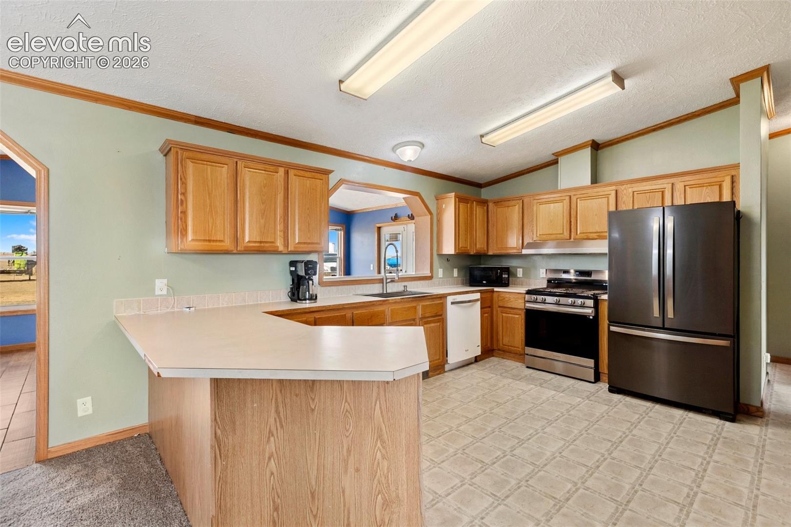 Kitchen featuring wood-finish cabinetry, a breakfast bar, and a stainless steel appliance suite including a refrigerator, range, and dishwasher