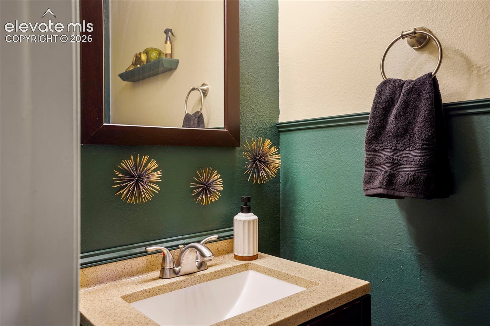Solid-surface vanity countertop with an integrated rectangular basin and dual-handle metal faucet, framed mirror, and crown-molding chair rail