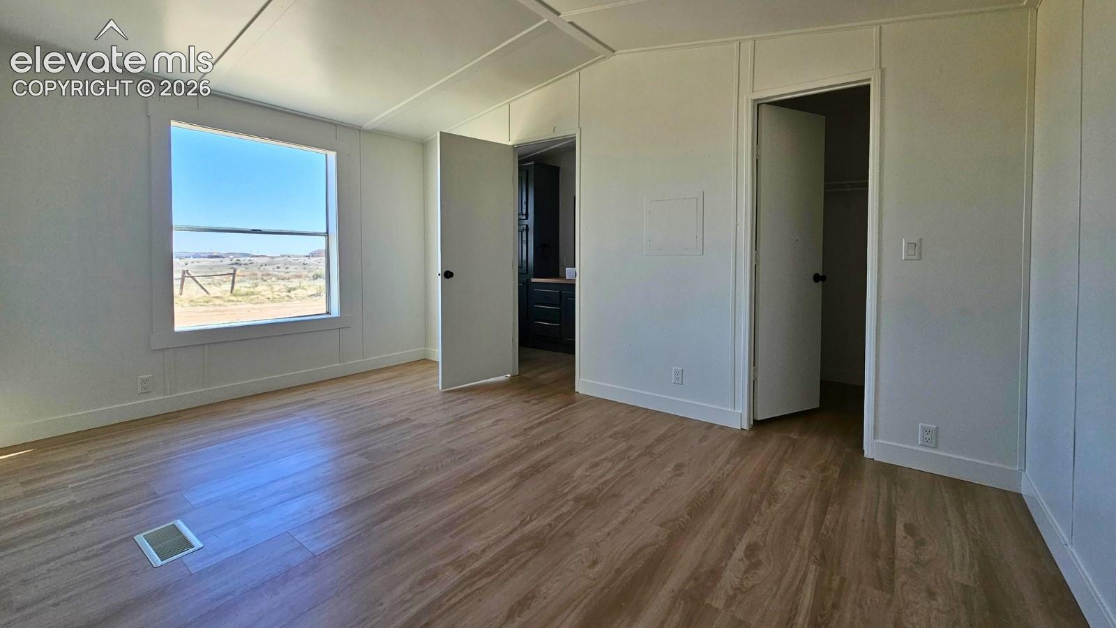 Interior space featuring wood-finish flooring, white walls, a large window, and two interior doors