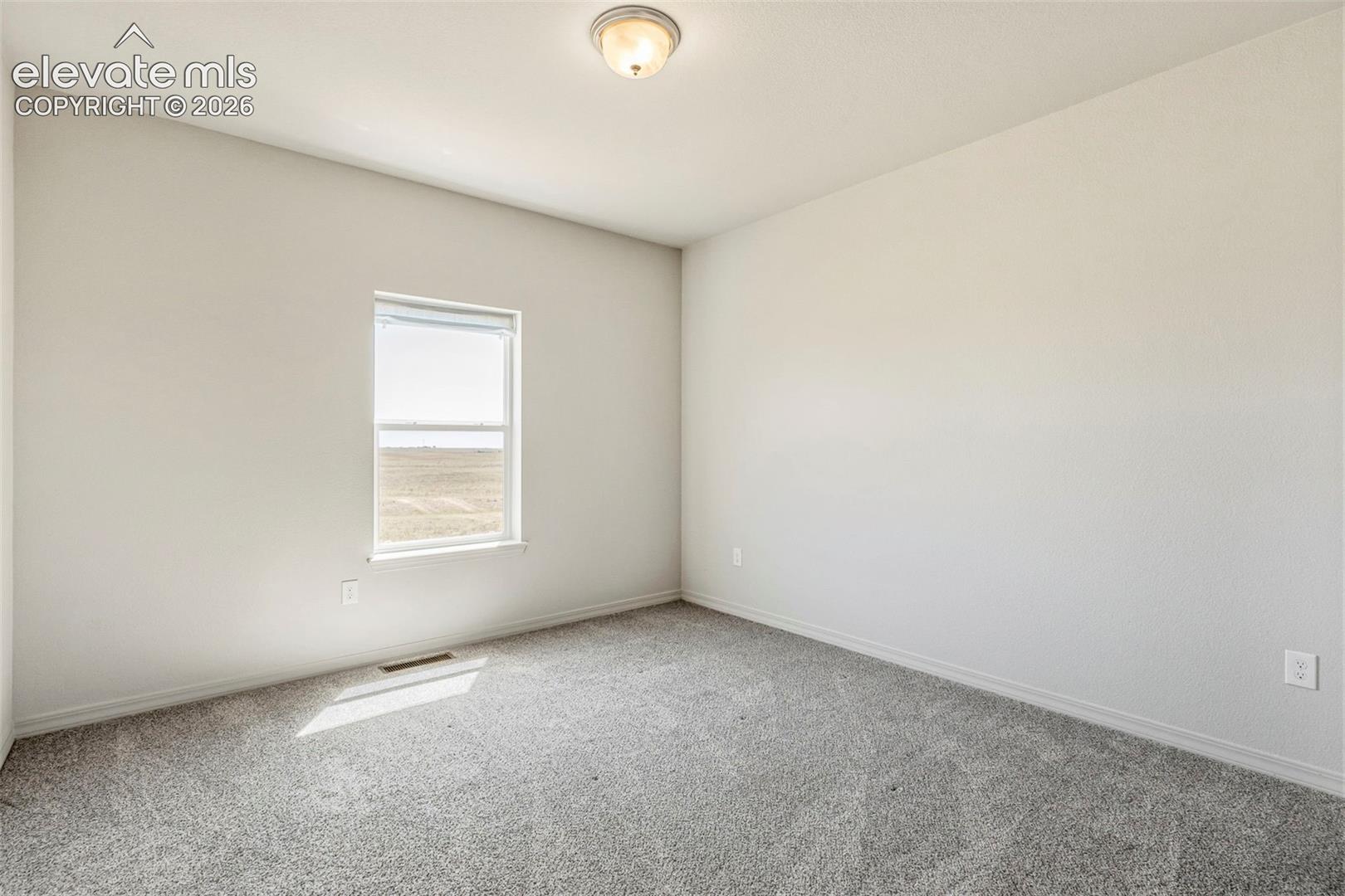 Neutral-toned room featuring a single window and gray carpeting