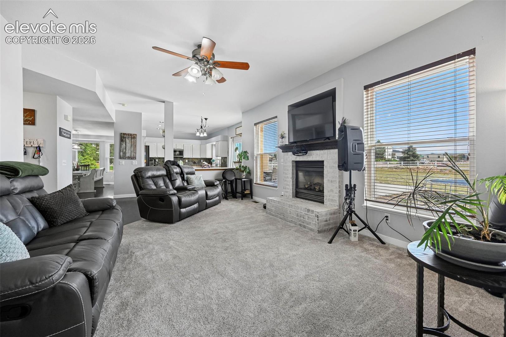 Living area featuring light gray carpeting and a white brick fireplace with a dark mantel