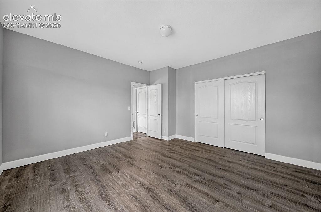 Wood-finish flooring, light gray walls, white trim, white paneled doors, and a flush mount ceiling light