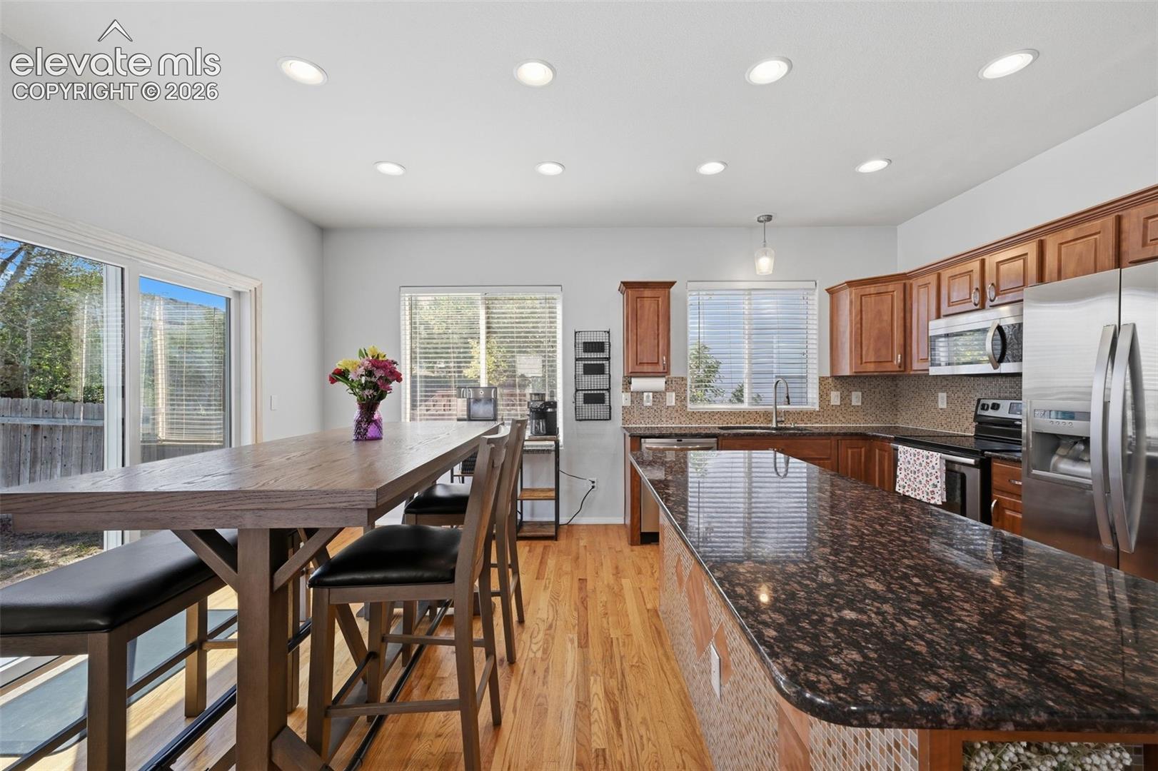 Kitchen featuring wood-finish flooring, recessed lighting, wood cabinetry, granite countertops, and stainless steel appliances