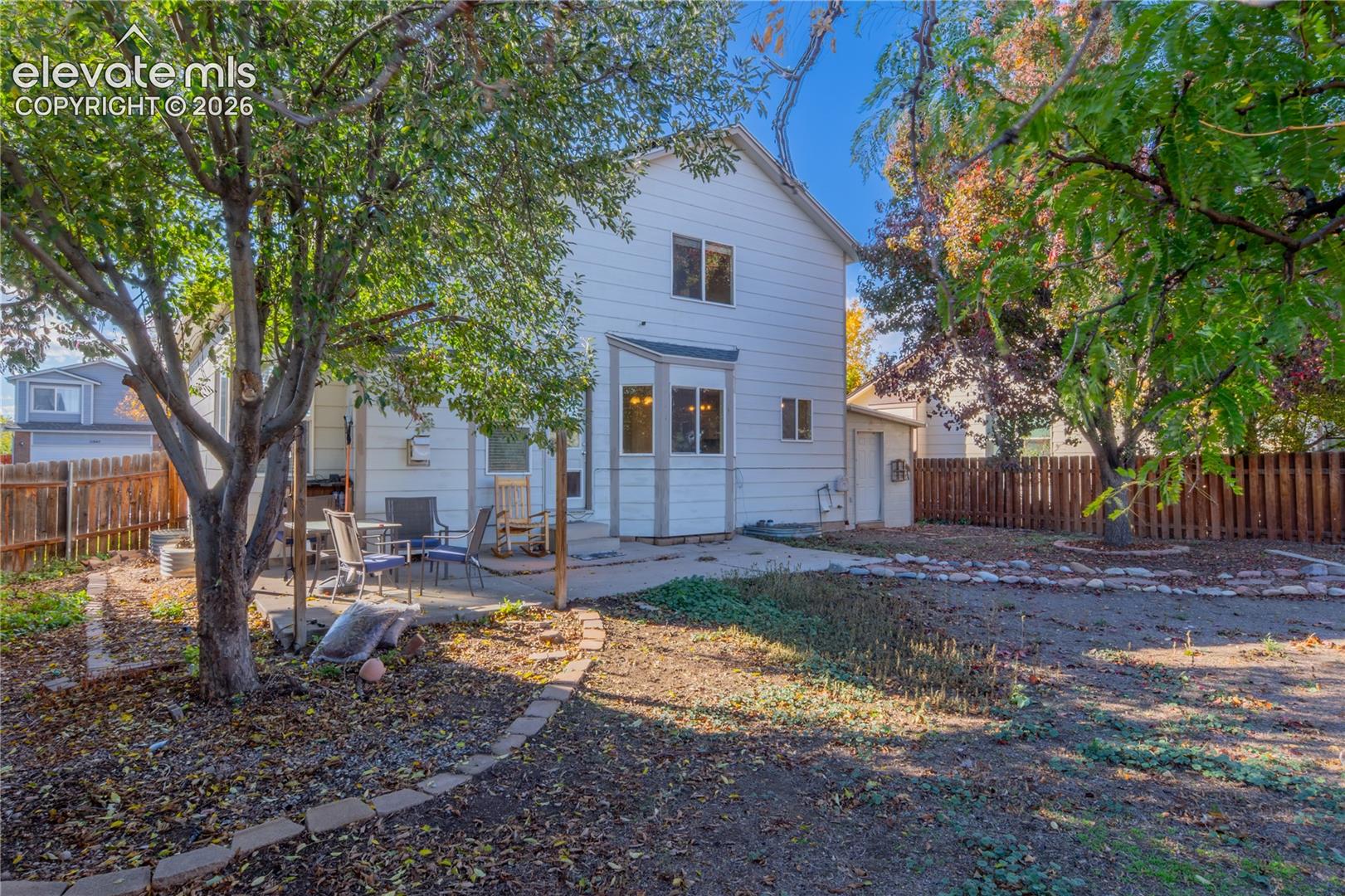 Mature shade trees frame the rear of the home, with a concrete patio for outdoor enjoyment.
