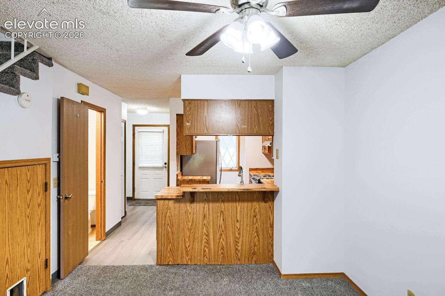 Kitchen pass-through with wood-finish cabinetry, stainless steel appliances, and a built-in breakfast bar