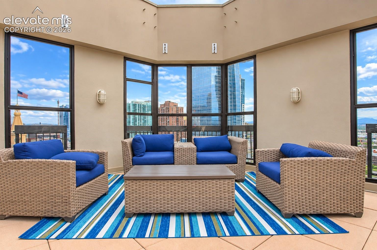 Expansive outdoor terrace featuring multiple large windows, recessed ceiling lights, and two wall-mounted light fixtures