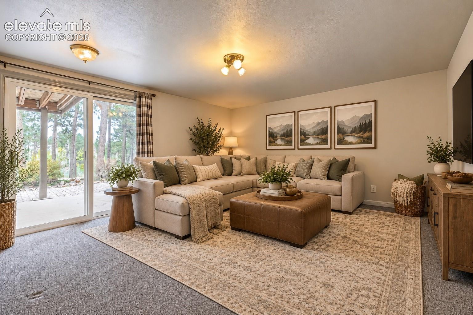 Recessed lighting illuminates a spacious living area featuring light-colored walls and grey carpeting