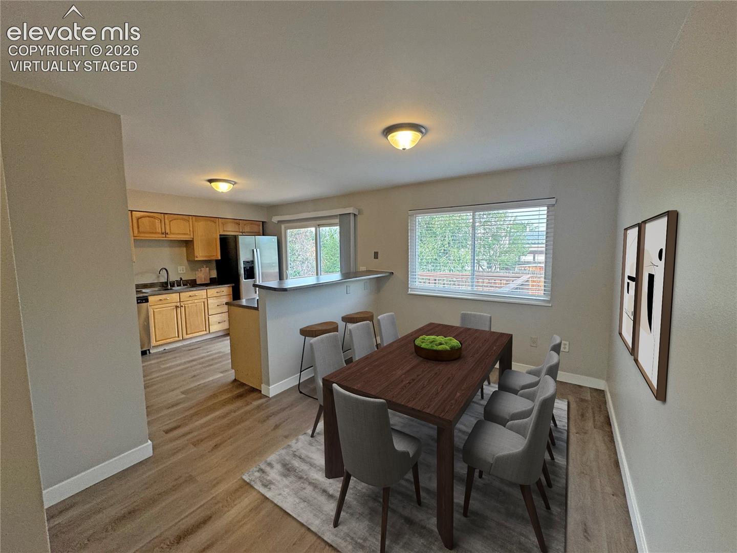 virtually staged Kitchen featuring wood cabinetry, integrated breakfast bar, and stainless steel refrigerator, complemented by wood-finish flooring