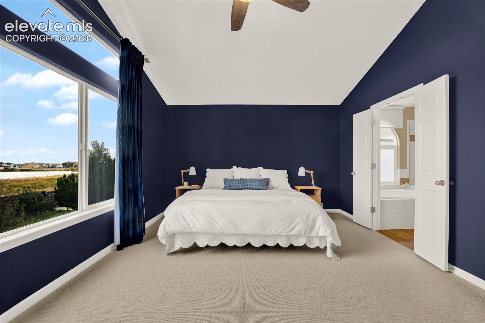 Vaulted ceiling with integrated paddle fan, expansive horizontal windows, and neutral carpeting