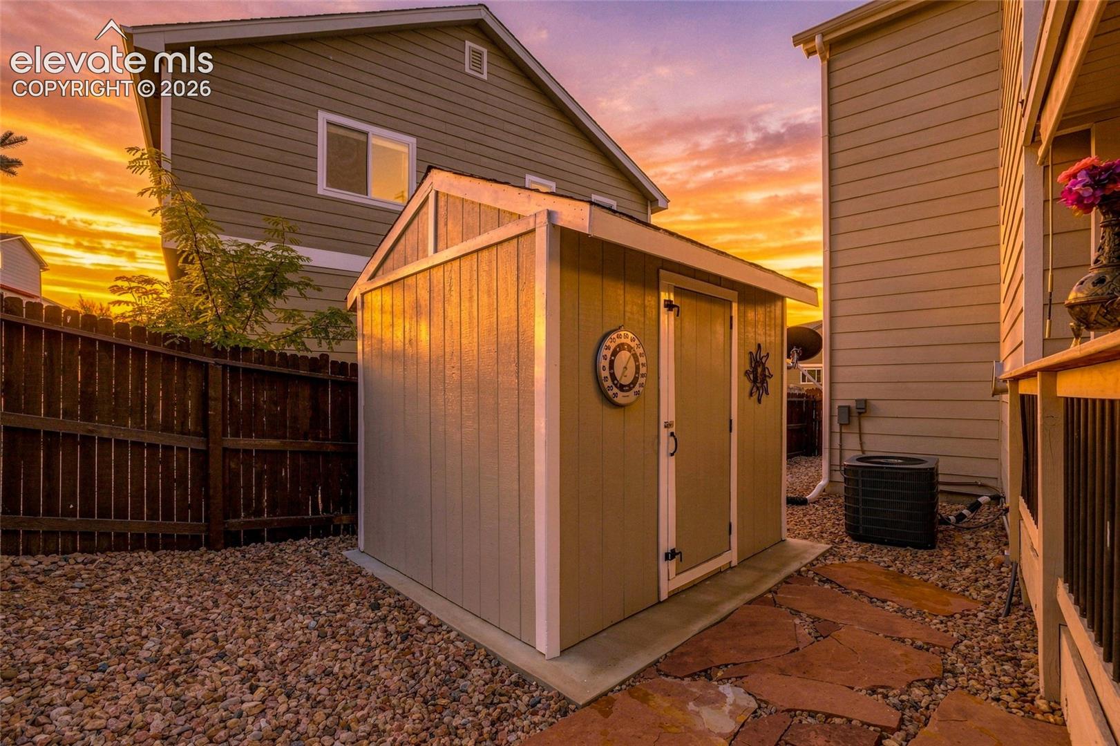 Storage shed with a pitched roof, gravel landscaping, and a flagstone pathway