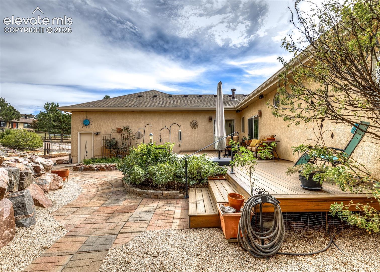 Private backyard sanctuary offers a spacious Trex deck, water feature, mature landscaping, vegetable garden and outdoor speakers.