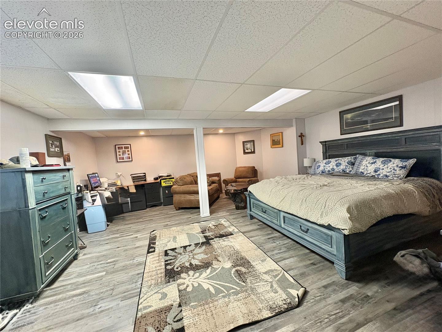 Wood-finish flooring throughout, drop ceiling with recessed lighting, and a structural column