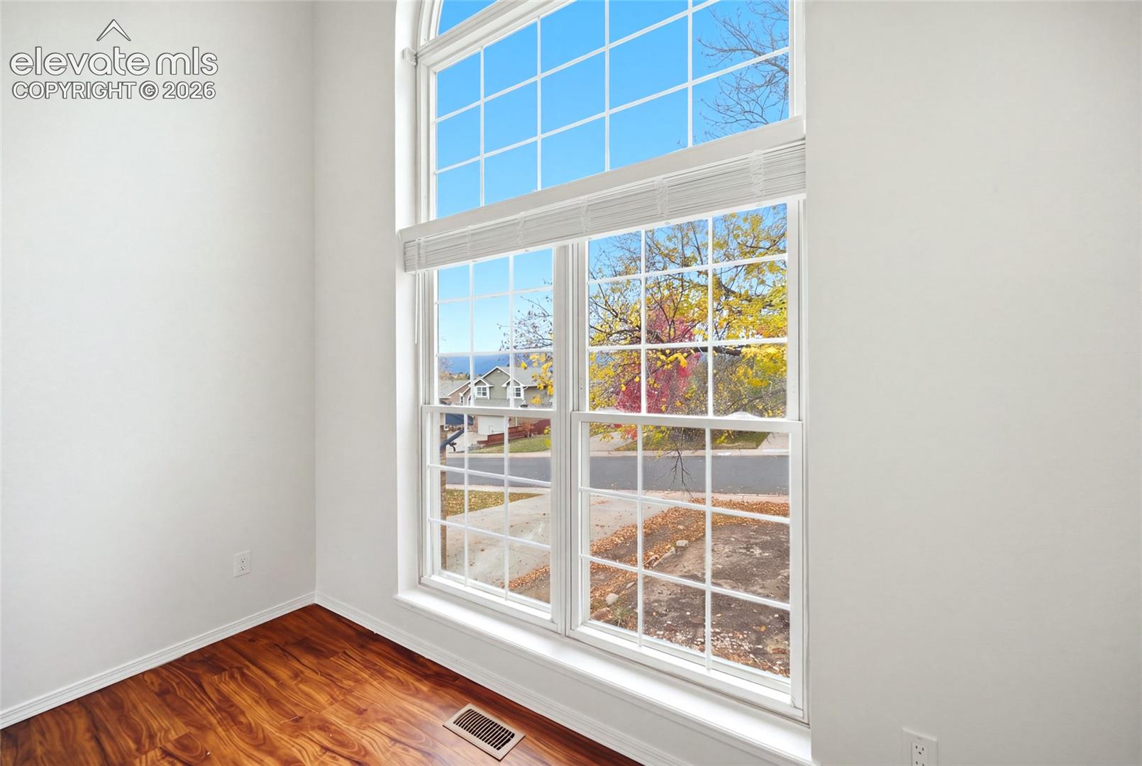 Floor-to-ceiling windows with grid detailing, arched top transom, and wood-finish flooring