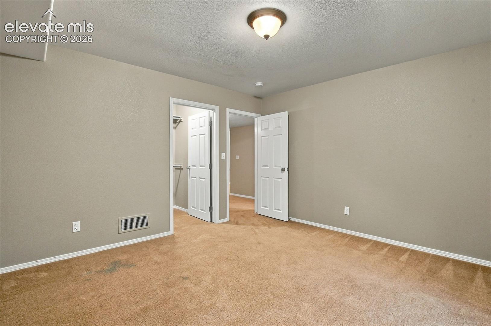 Carpeted flooring, neutral wall color, ceiling-mounted light fixture, white trim, and white paneled doors