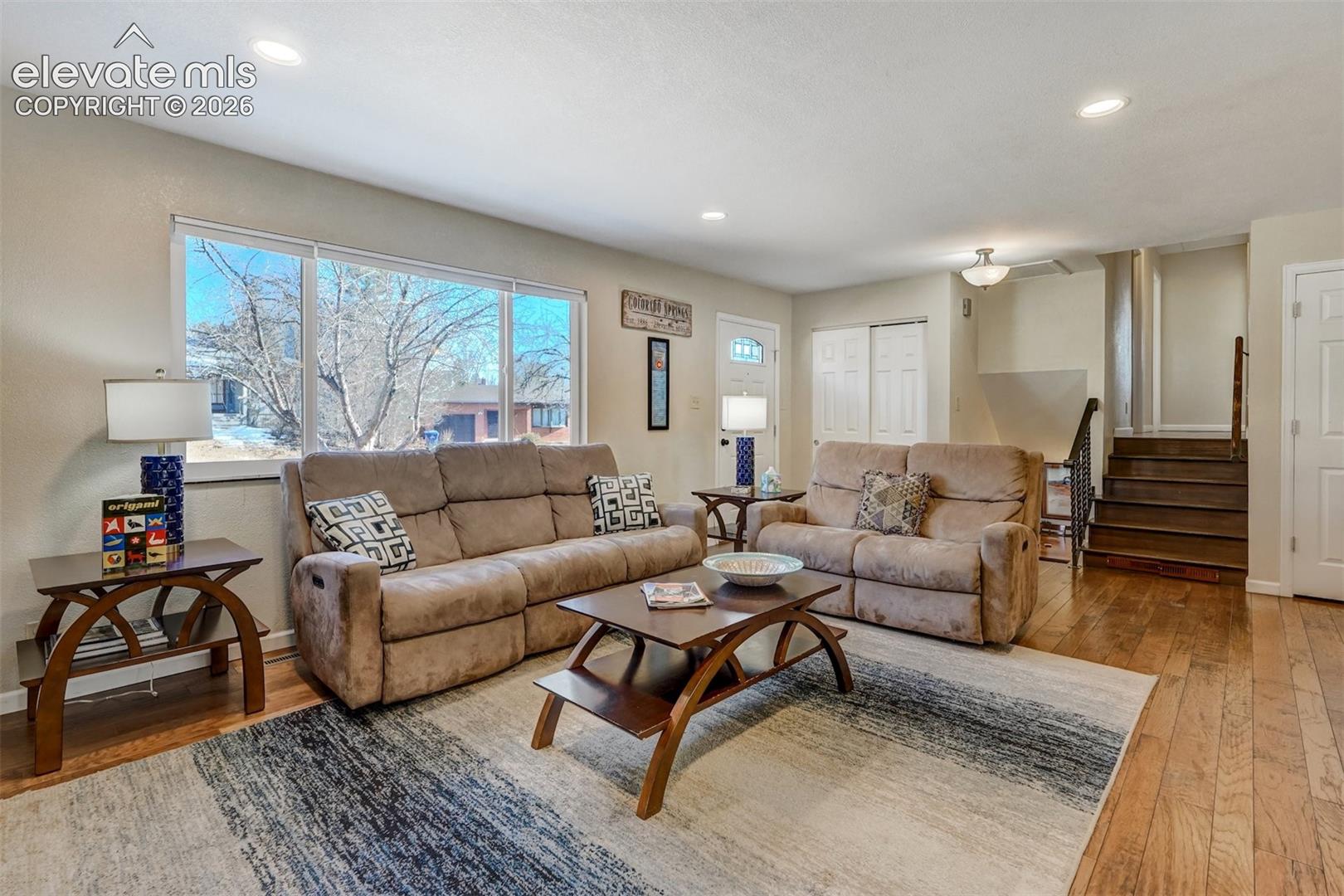 Hardwood flooring, recessed lighting, large picture windows, white trim, and a built-in staircase