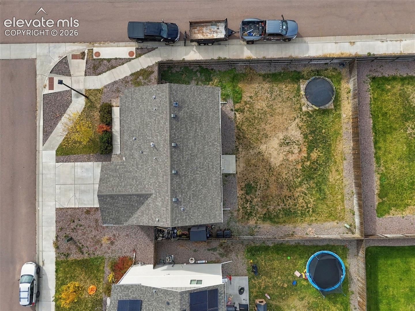 Corner lot featuring a shingled roof, concrete walkway, and fenced perimeter