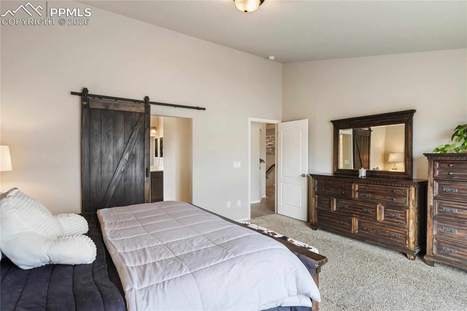 Spacious primary bedroom featuring vaulted ceilings, a large window, and soft carpeting