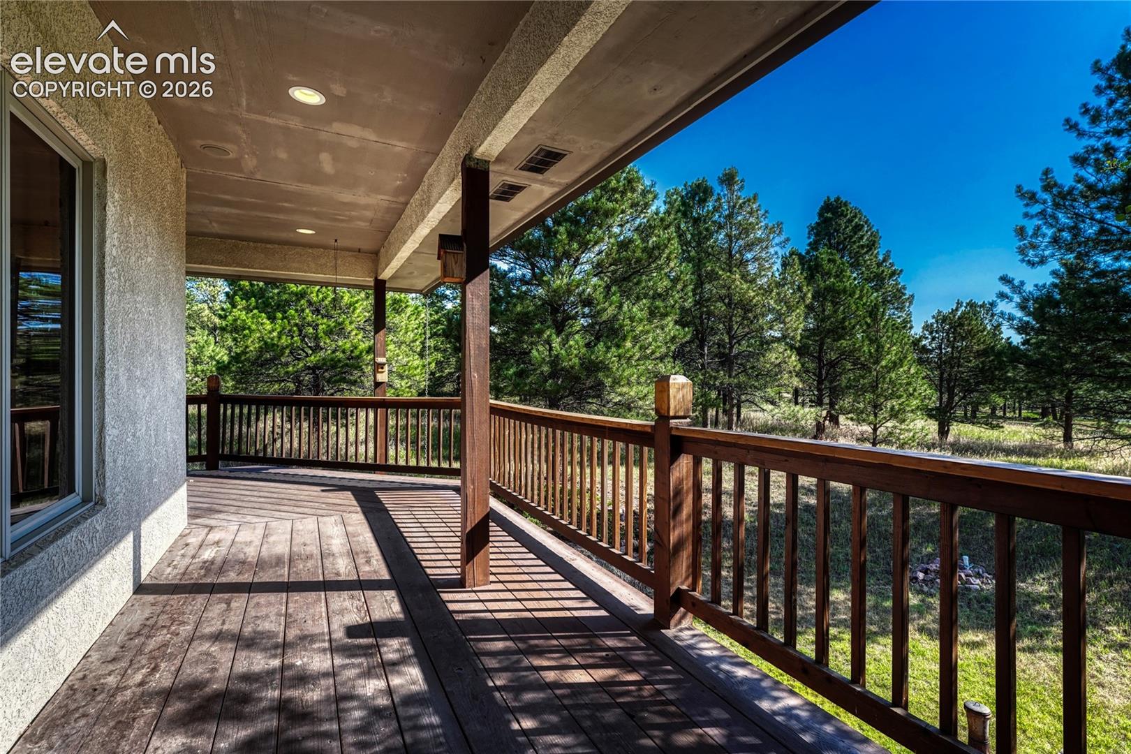 Covered wraparound wood deck along the back and side of the home.