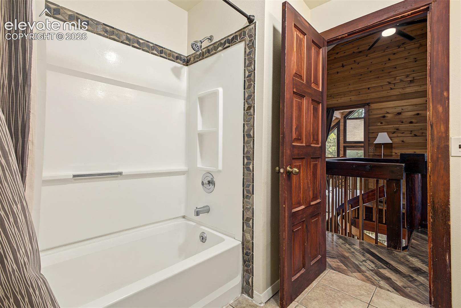 White bathtub with chrome fixtures and an integrated shelving unit
