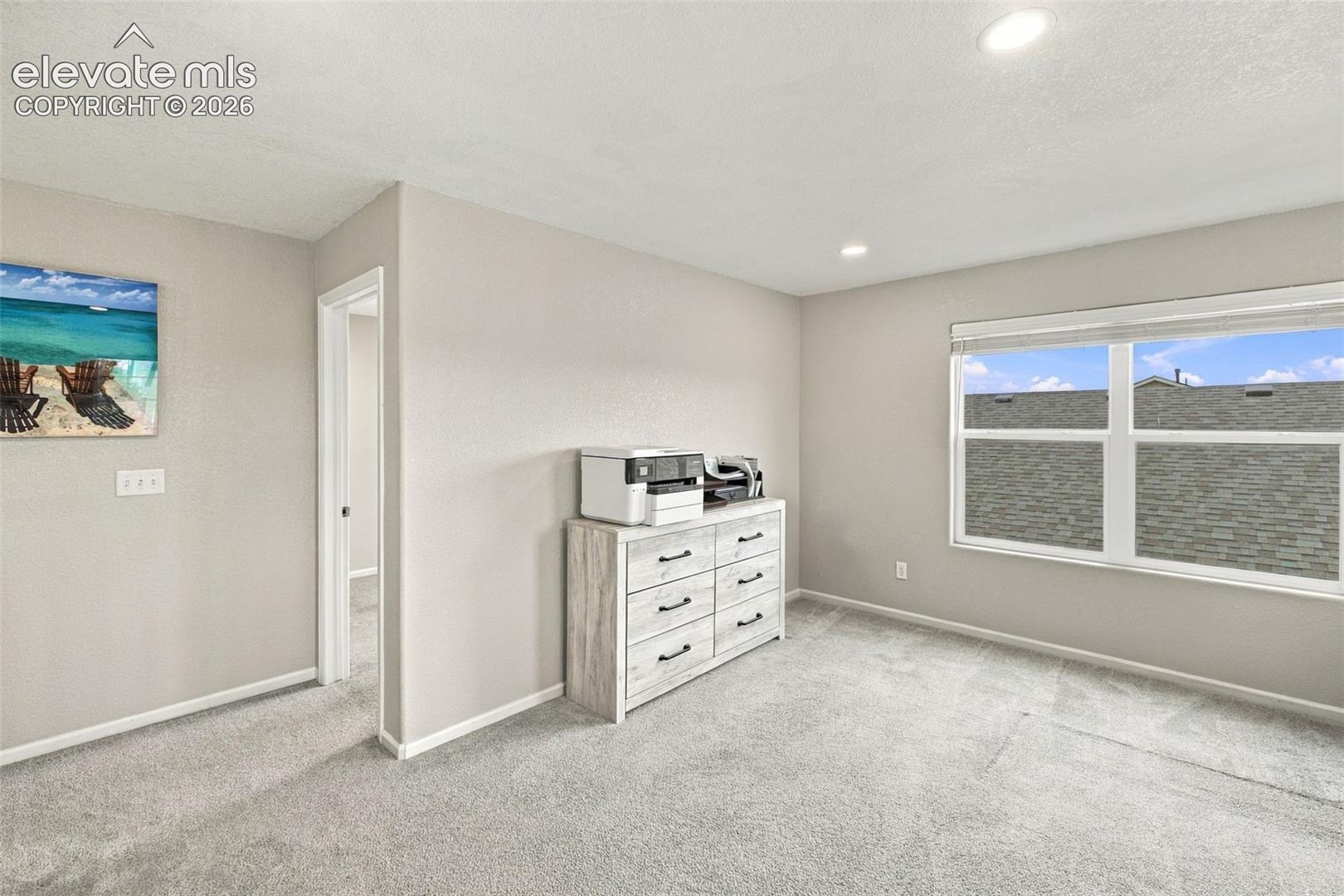 Room featuring neutral wall tones, wall-to-wall carpeting, recessed ceiling lighting, and a large multi-pane window