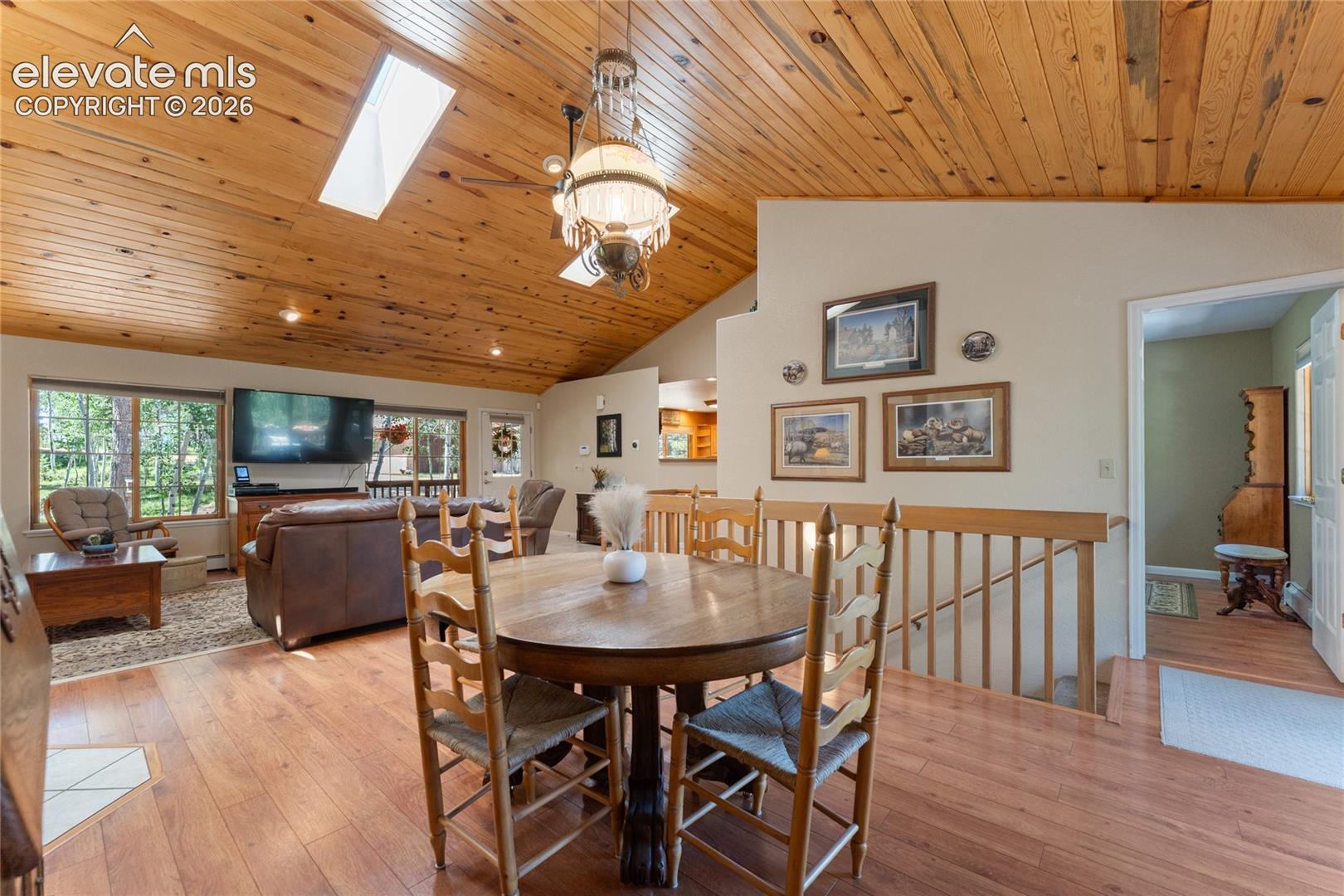 Vaulted wood-paneled ceilings with skylights, wood-finish flooring, and a decorative chandelier