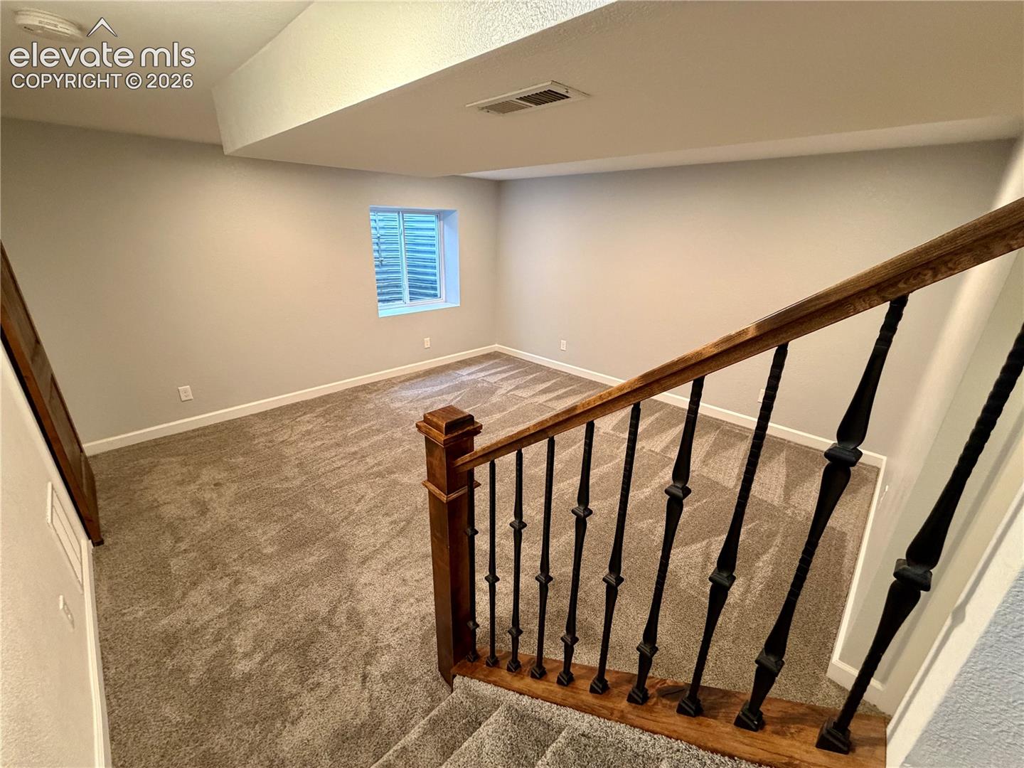 Furniture removed-Finished lower level featuring neutral carpeting, light gray wall paint, white trim, and a window with blinds