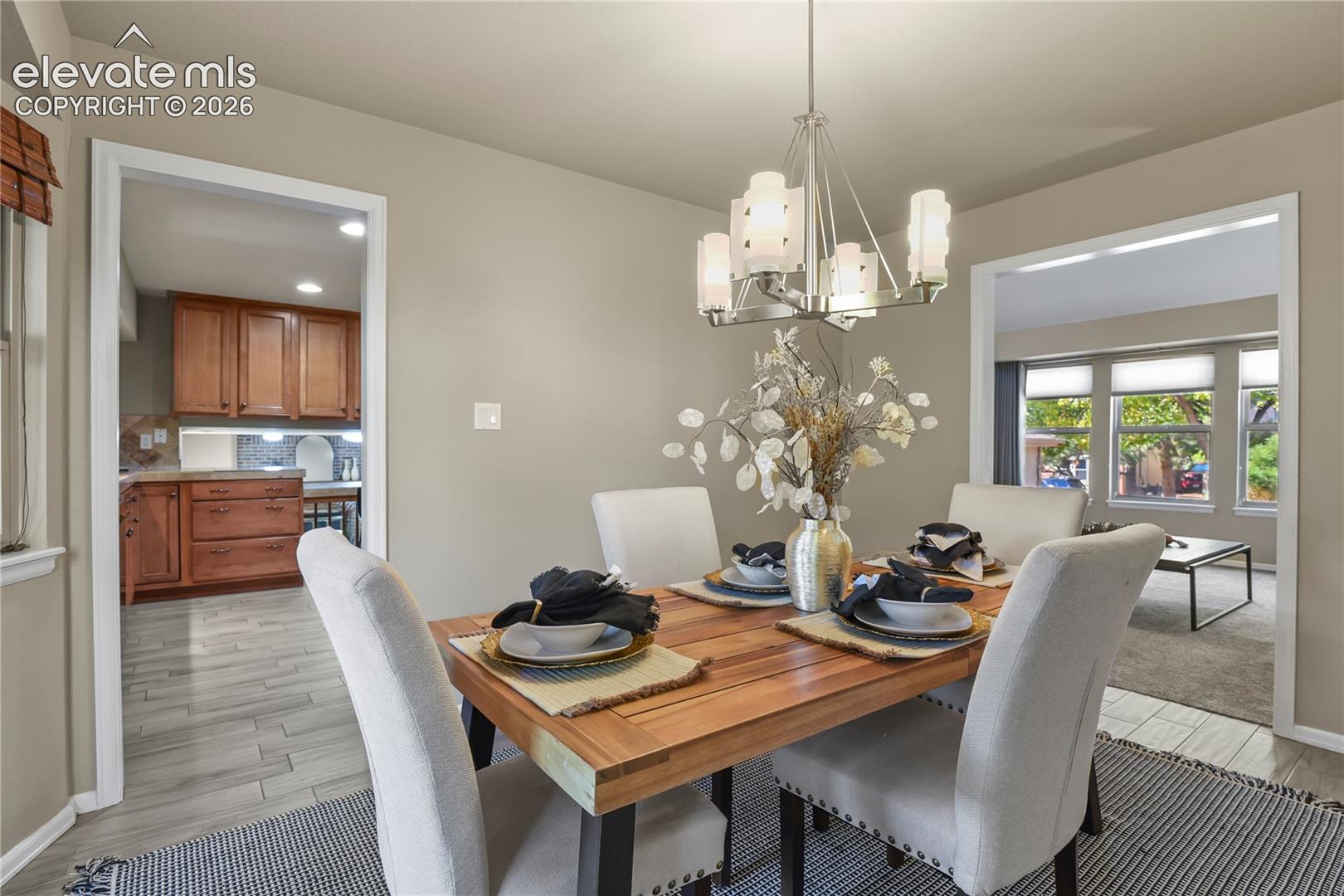 Dining area featuring wood-finish tile flooring, a multi-light brushed nickel chandelier, and neutral wall tones