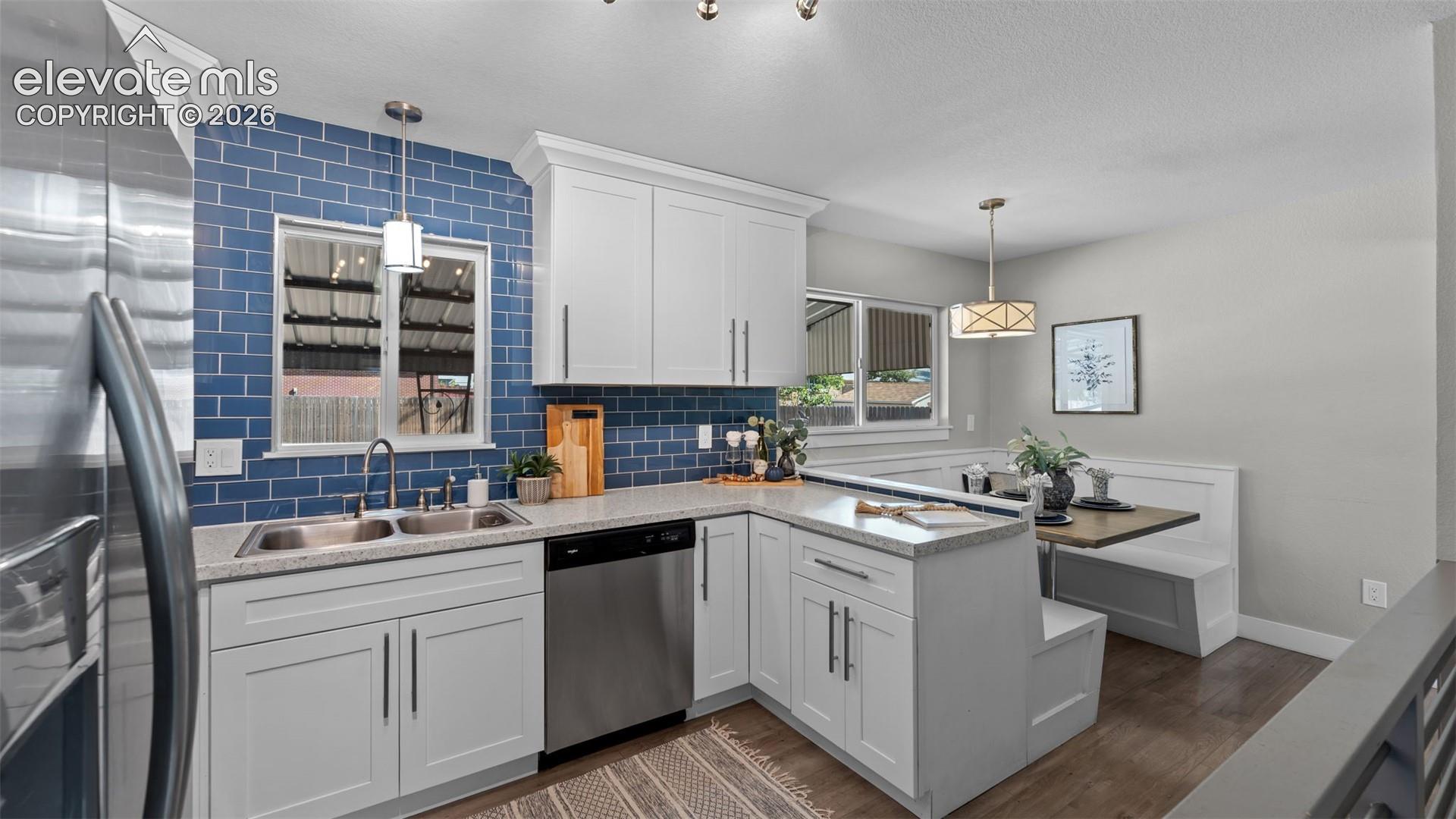 Kitchen featuring white shaker cabinetry, stainless steel dishwasher, double basin sink, and a built-in dining nook