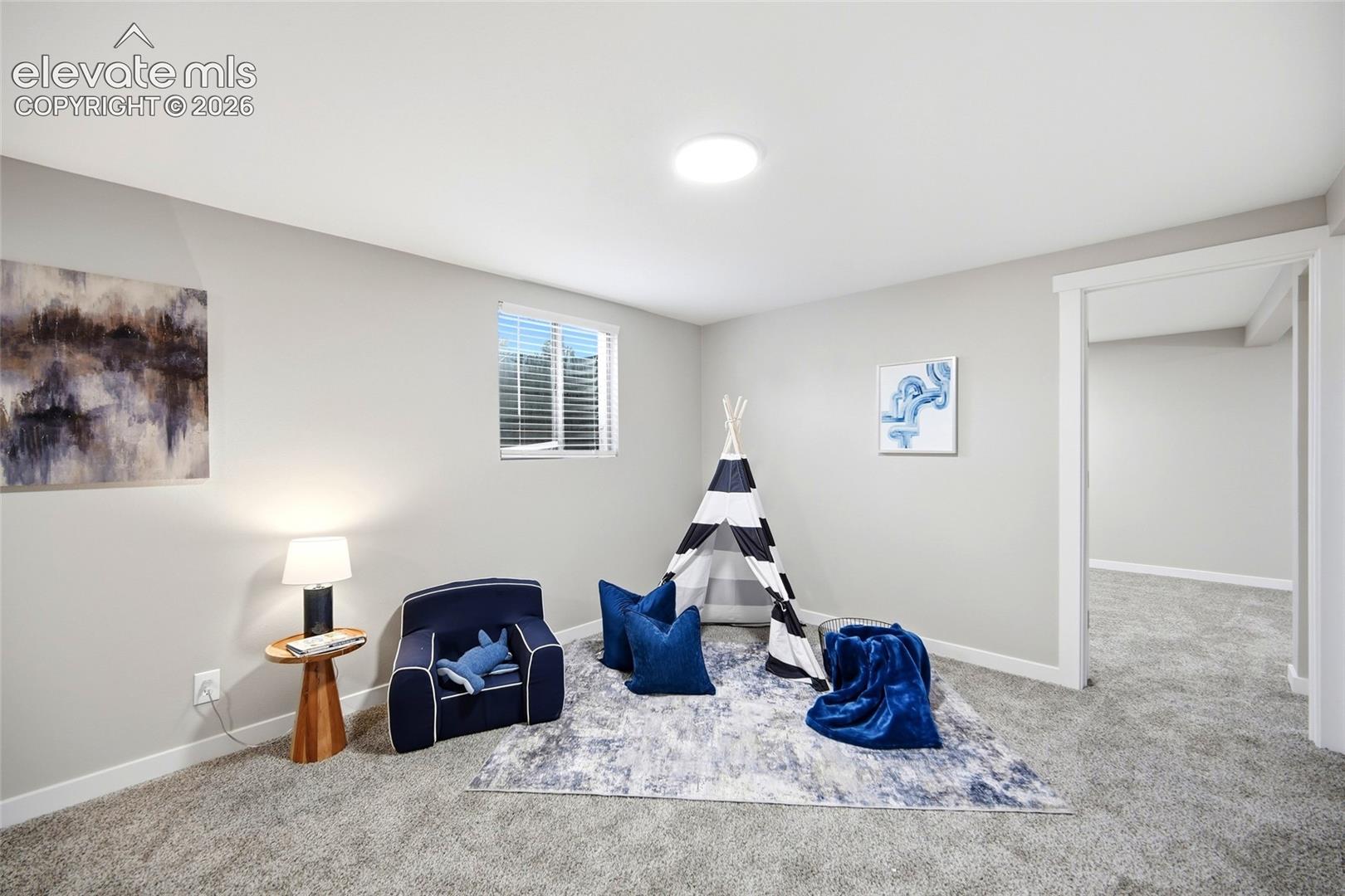 Recessed circular light fixture, window with blinds, light gray wall paint, and gray carpet flooring