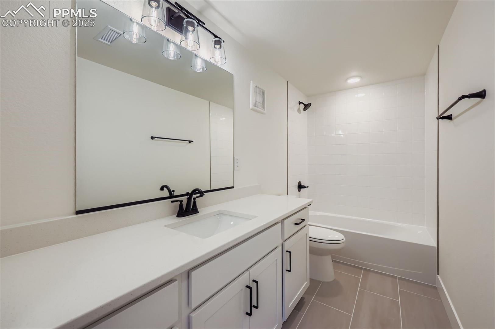 Full bath with vanity, light tile patterned floors, and shower / washtub combination