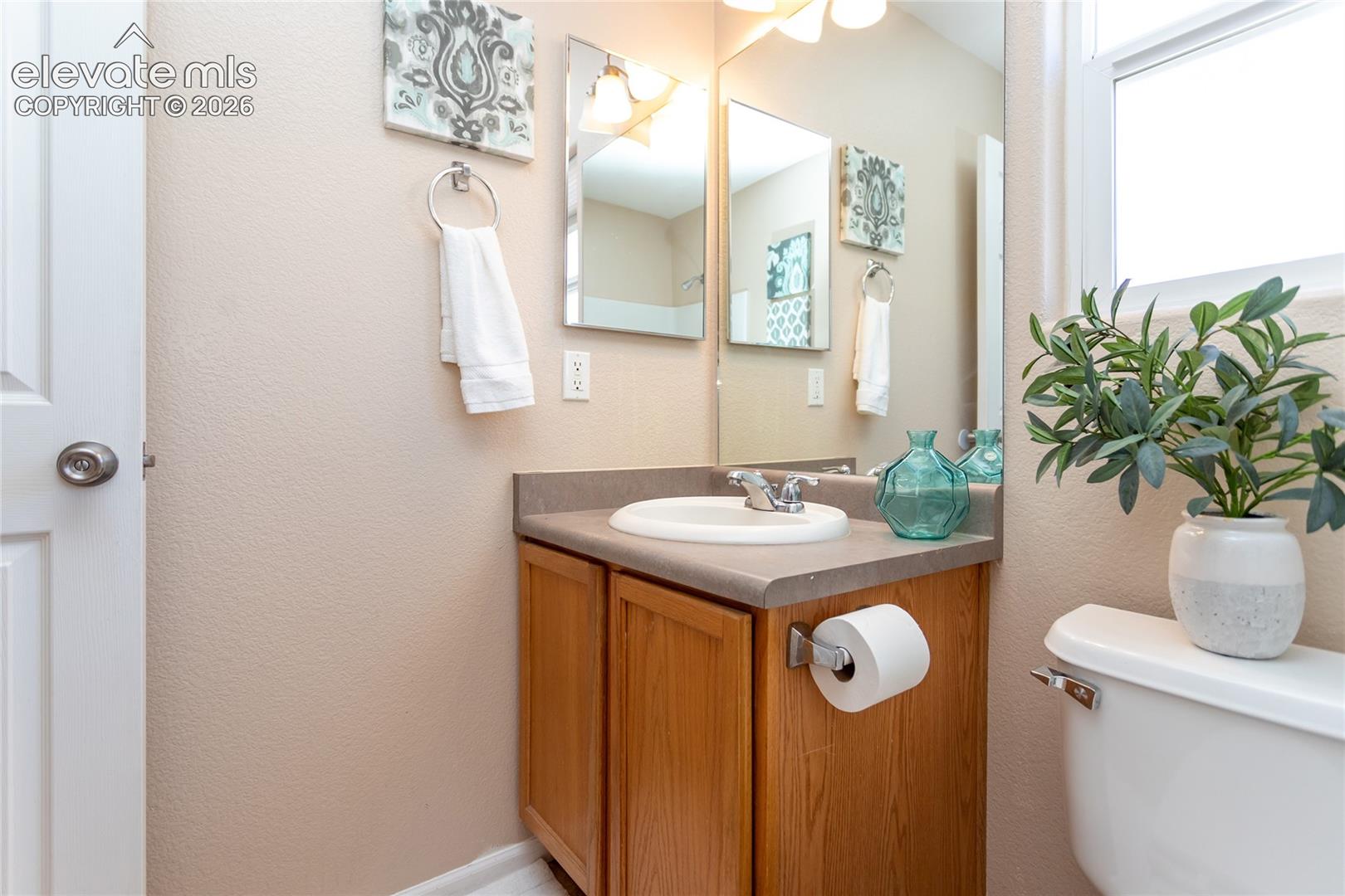 A second full bath vanity area includes a single sink, large wall mirror, and oak storage cabinet