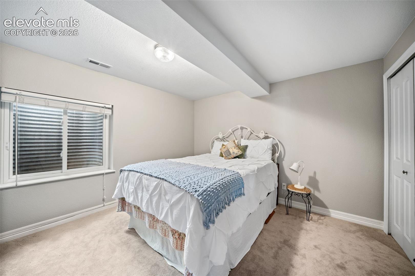 Bedroom featuring neutral wall paint, light-colored carpeting, and a white window frame