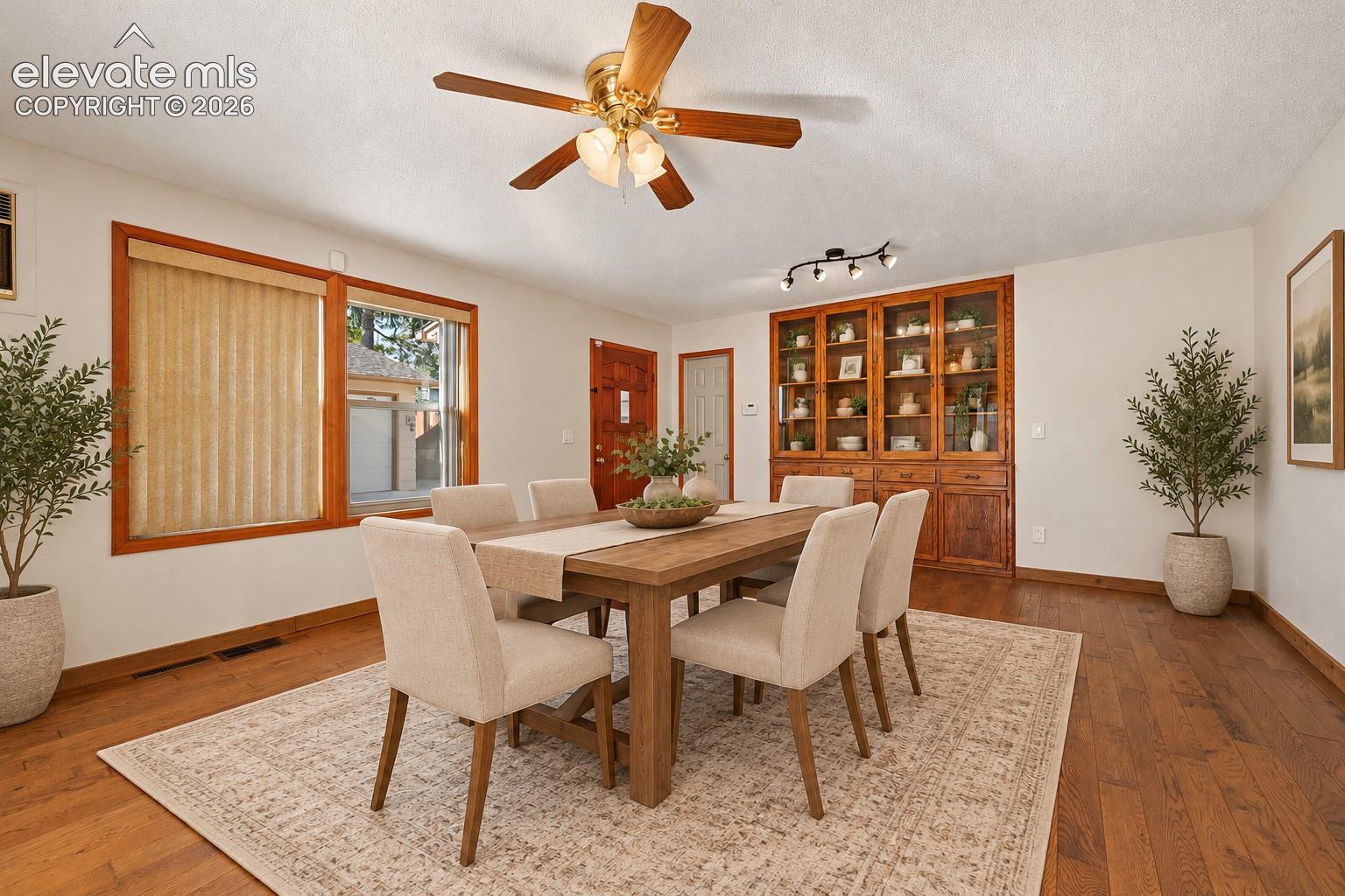 Wood-finish flooring, built-in wooden display cabinetry, recessed track lighting, ceiling fan with light fixture, and wooden window trim