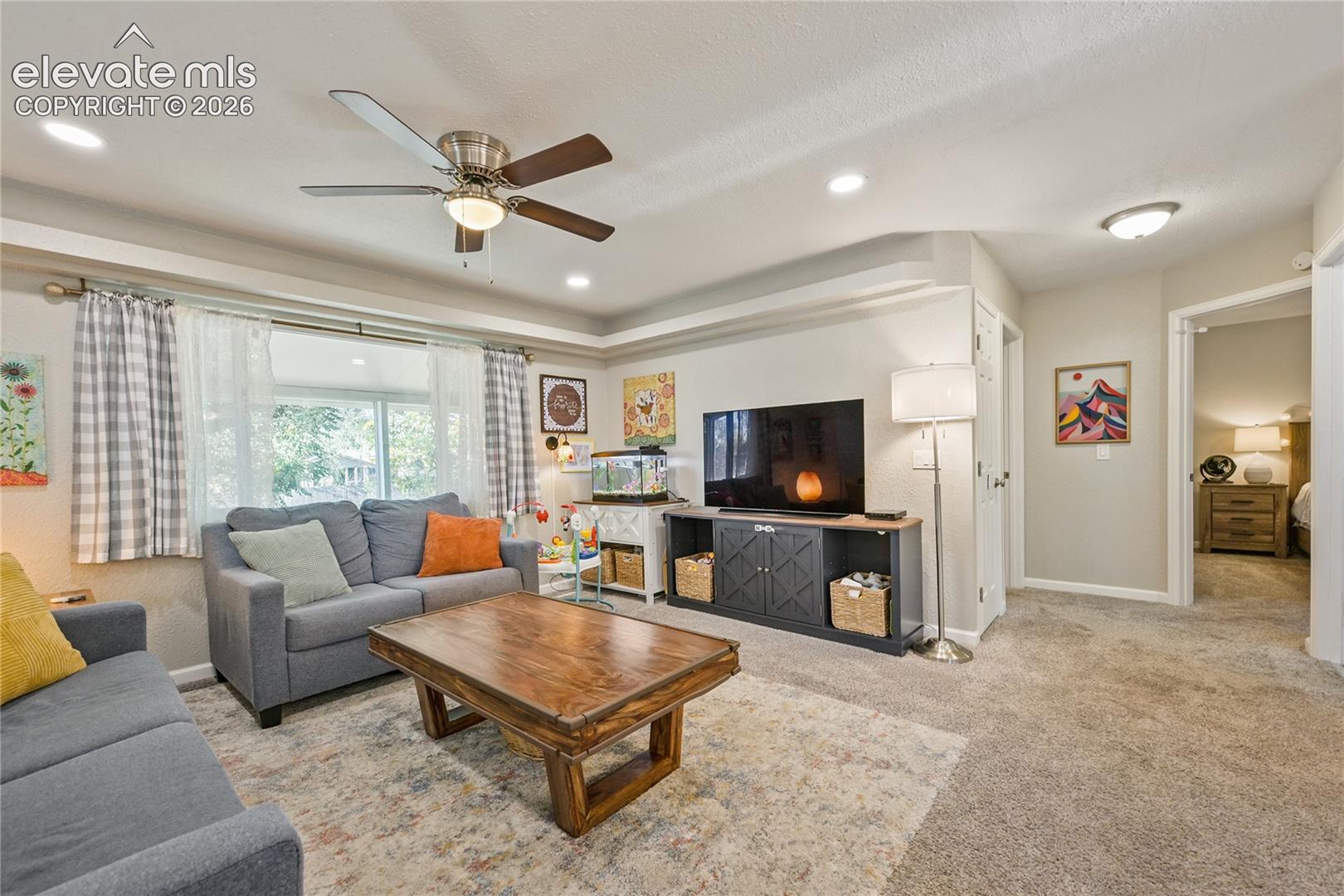 Neutral-toned interior featuring recessed lighting, a ceiling fan with integrated light, a wide multi-pane window, and wall-to-wall carpeting