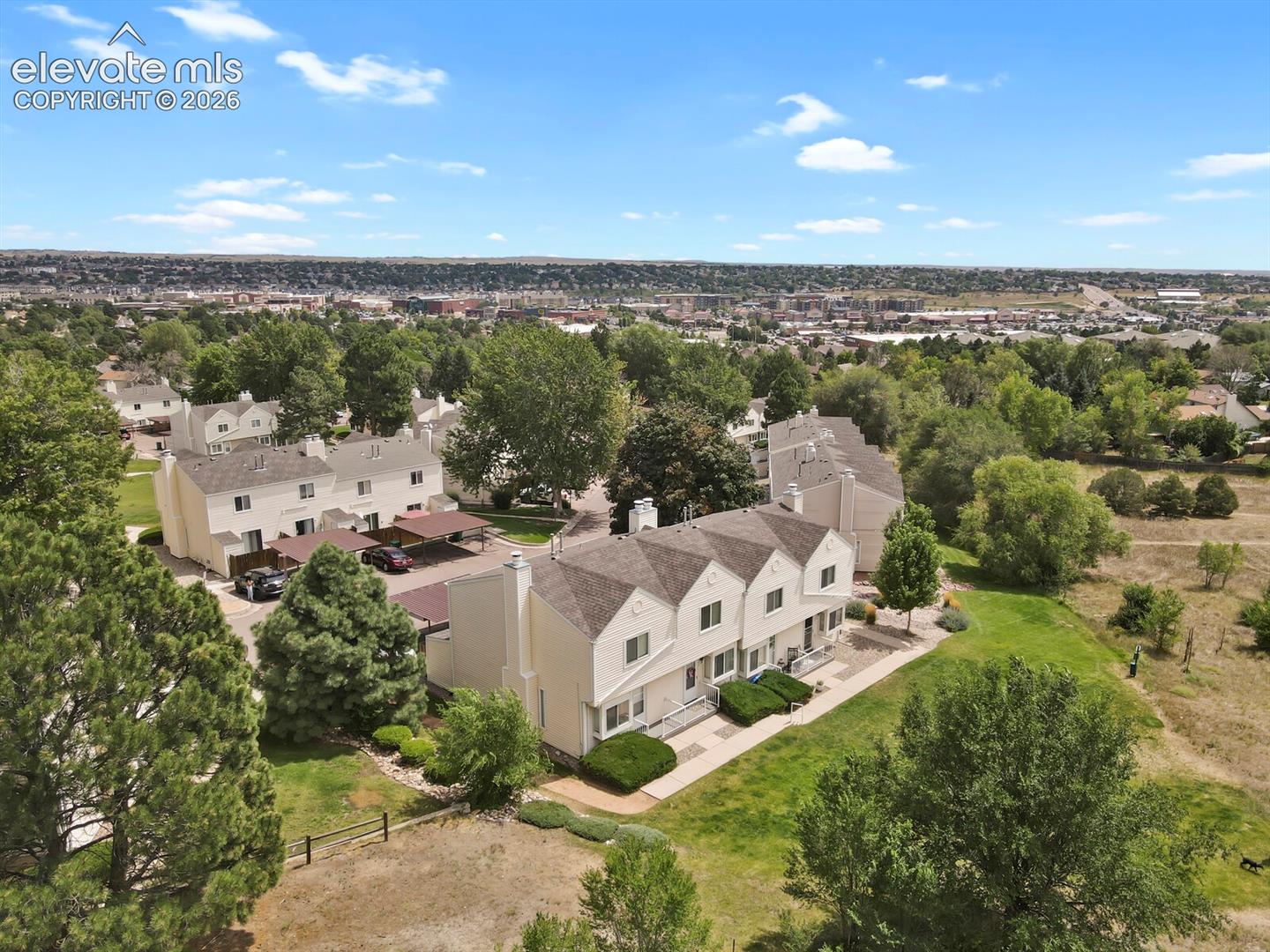 Townhome community featuring neutral-toned exteriors, pitched roofs, and multiple attached carports