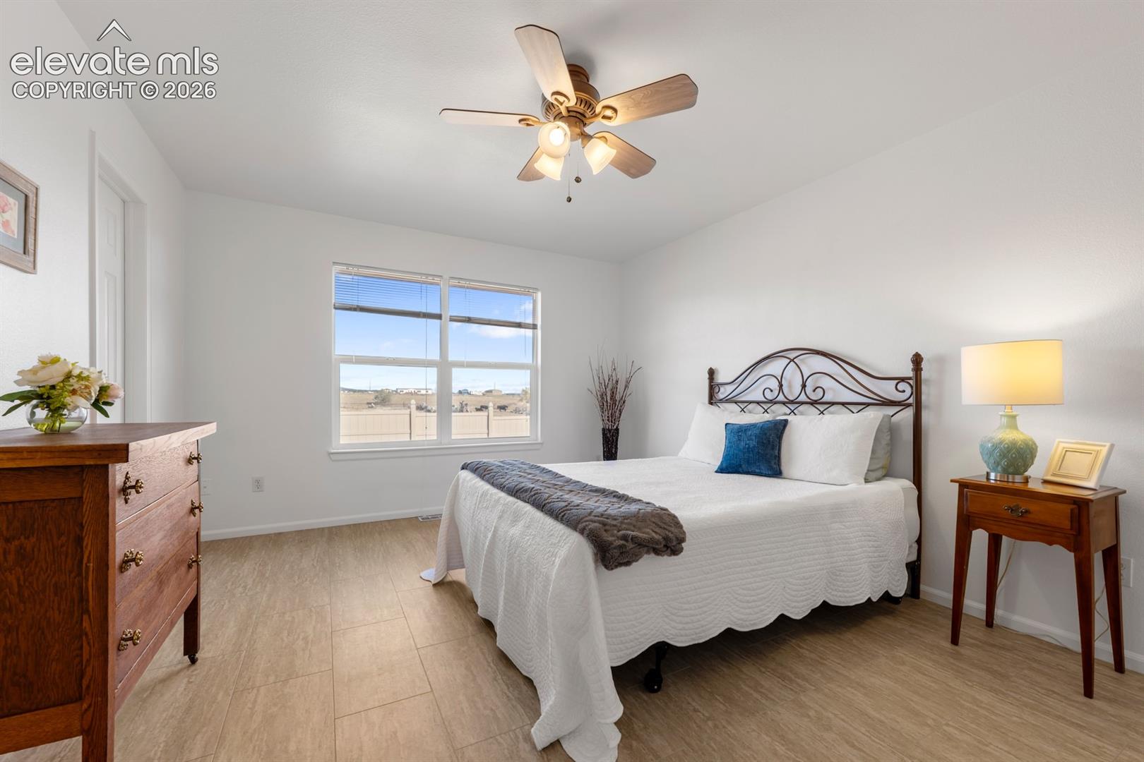 Room featuring wood-finish flooring, a multi-blade ceiling fan with integrated lighting, and dual-pane windows