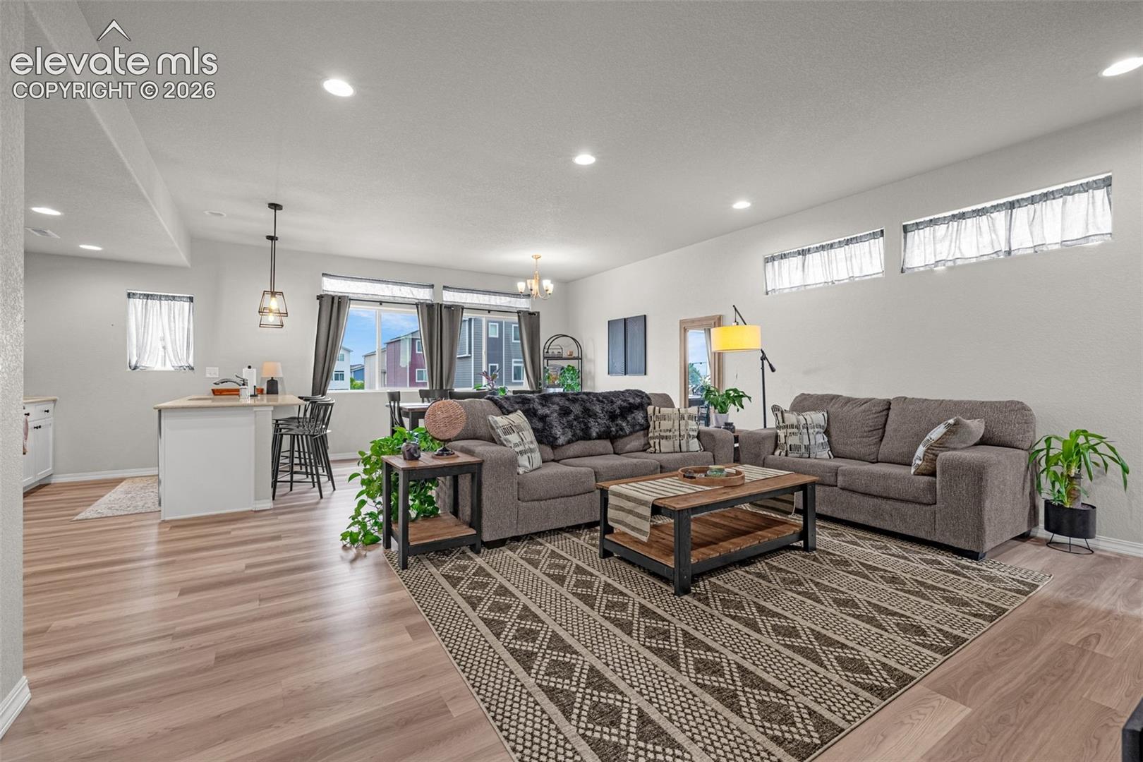 Open-concept living area featuring wood-finish flooring, recessed lighting, and a kitchen peninsula with bar seating