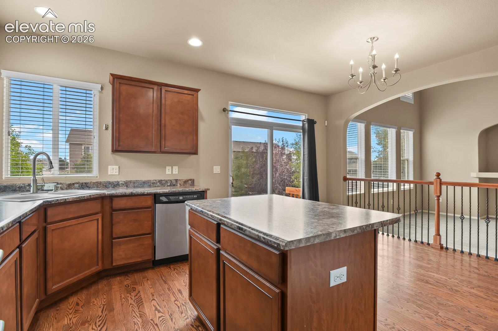 Kitchen featuring wood-finish flooring, dark wood cabinetry, and stone-finish countertops