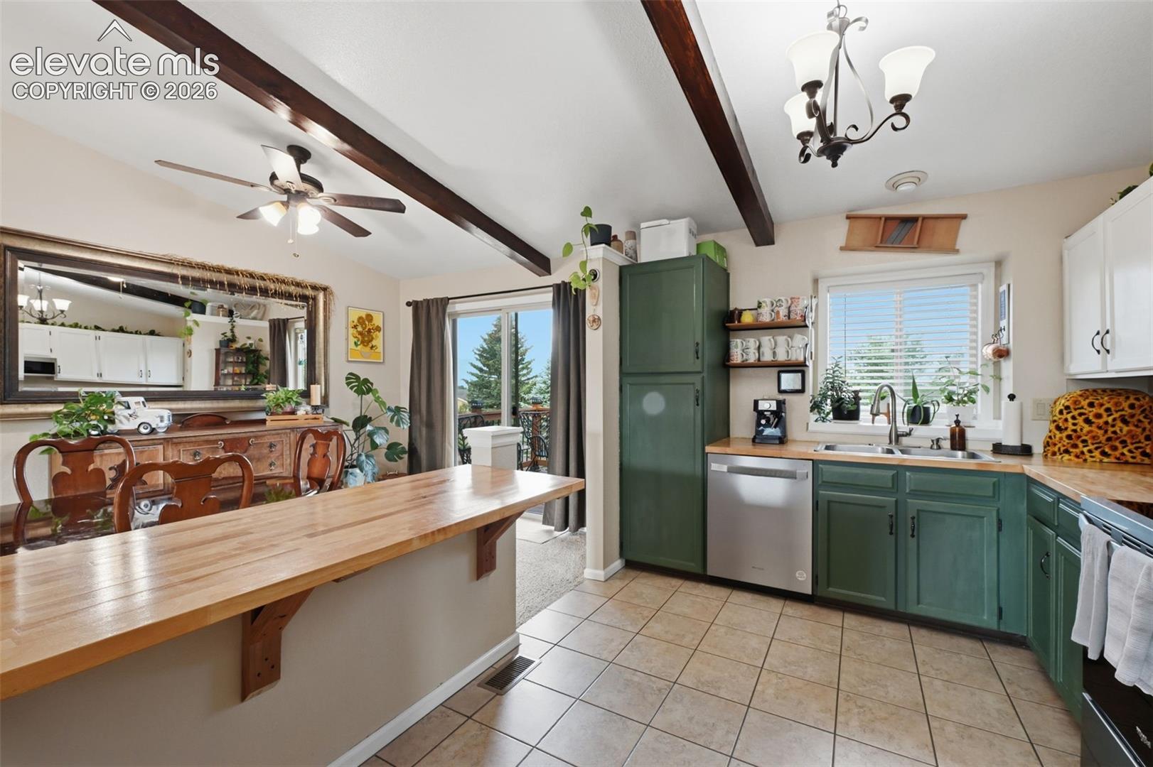 Kitchen featuring exposed ceiling beams, a wood-finish countertop island, tile flooring, and a stainless steel dishwasher