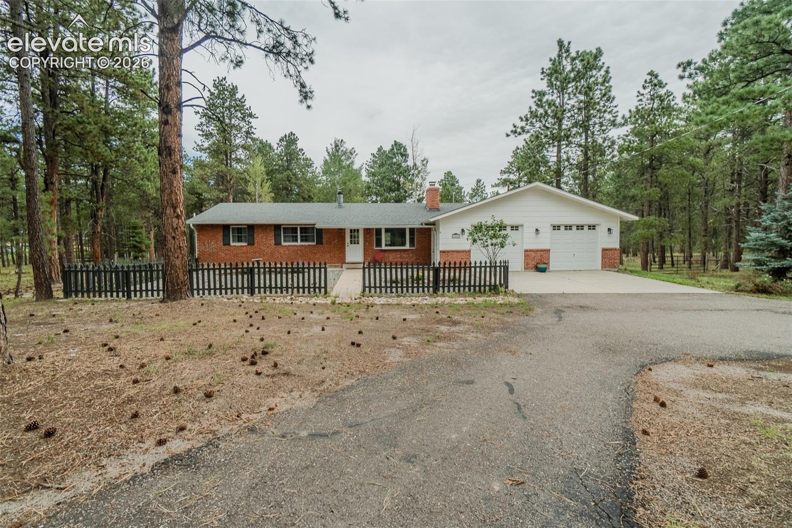 Black Forest acreage living at its best! This charming ranch-style home offers 5 bedrooms, 3 bathrooms, and 5 fully fenced acres surrounded by tall ponderosa pines and expansive meadows. The fully fenced yard provide plenty of space for animals, recreation, and enjoying the peaceful setting.Inside, the cozy living room welcomes you with a wood-burning fireplace framed by a classic brick surround and flows seamlessly into the dining area and kitchen. The kitchen features white cabinetry, granite countertops, and stainless steel appliances. The main level also offers a versatile space—perfect for a bedroom, home office, gym, playroom, or second lounge area. The spacious primary suite is a true retreat with a beautifully remodeled en suite bathroom. A second bedroom and full bathroom complete the main level.Downstairs, you'll find a large family room with another wood-burning stove, two additional bedrooms, a full bathroom, and a huge laundry room, offering plenty of room for everyone.The oversized attached 2-car garage provides abundant space for vehicles and storage.Outside is where this property truly shines. Relax on the massive deck while taking in the peaceful views of your acreage. A loafing shed and tool shed are already on site, and with no HOA, you have the freedom to add another outbuilding or create the property you've been dreaming of. If you're looking for privacy, space, and the freedom to enjoy your land, this unique Black Forest property is one you won't want to miss.