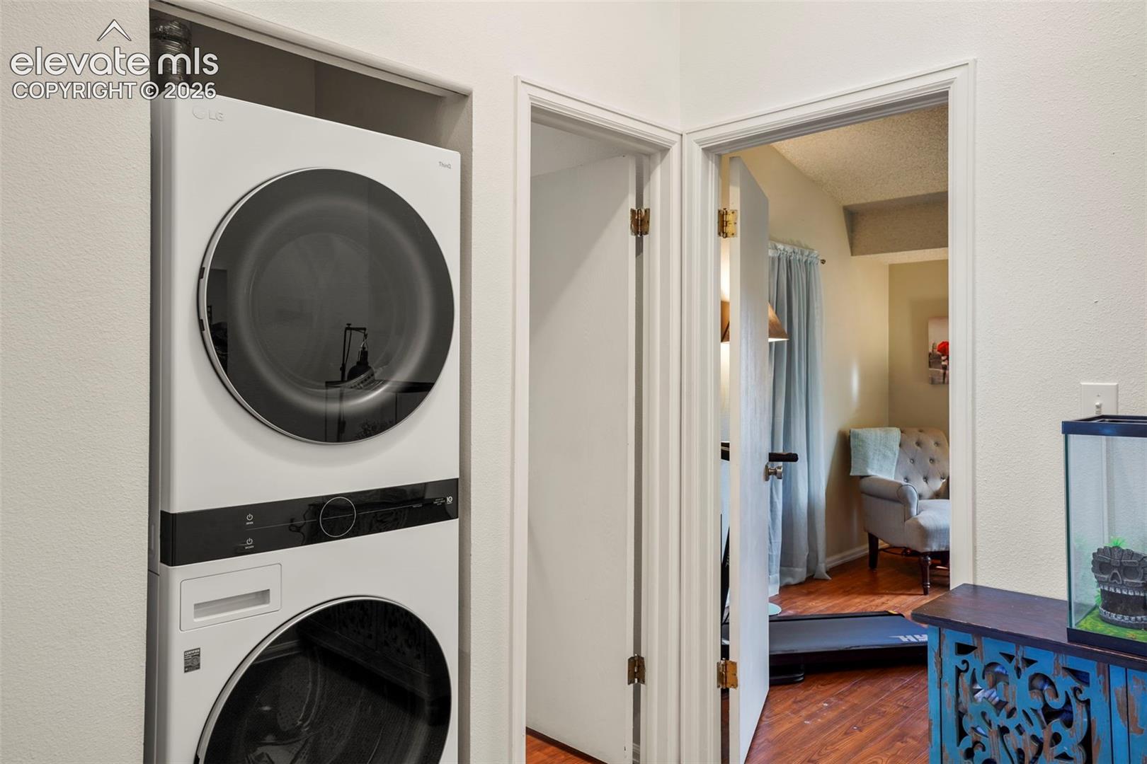 Stacked laundry unit with front-loading washer and dryer, finished with smooth-surfaced cabinetry and casing trim