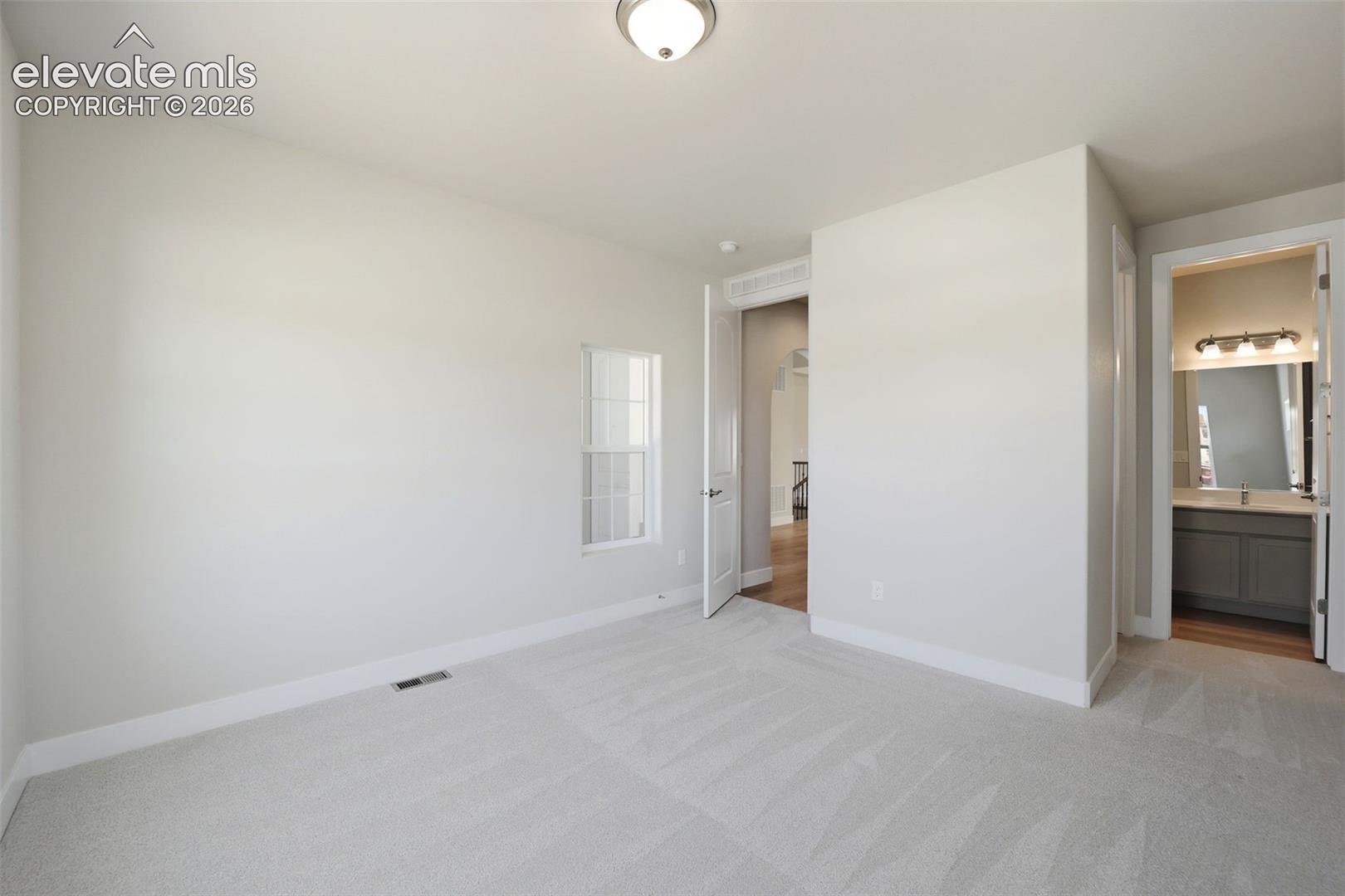 Neutral interior space featuring carpeted flooring, a flush-mount ceiling light, a single-hung window, and a multi-panel door
